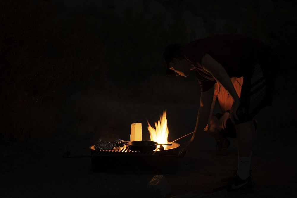 A pan over a small campfire at night