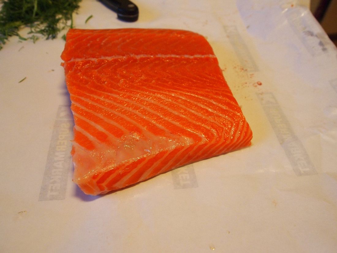 A salmon fillet covered in salt for curing